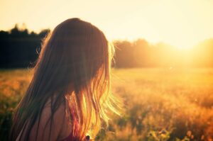 Ung pige står på marken og ser på solopgang. Kroppen husker mobning